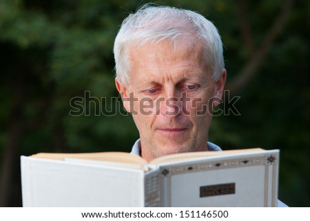 Closeup portrait of skinny  old man reading book in the park outdoor