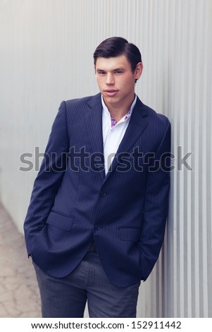 Handsome guy in business suit with hairstyle on urban background