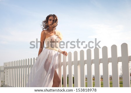 Fashionable model in bride dress posing outdoors. Flying hair
