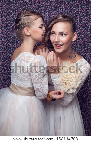 Model girls whisper in ear. two exclusive long white  identical dresses