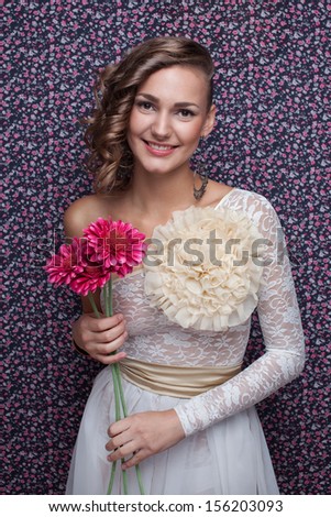 Smiling young woman in white long dress with flower in hand. Vogue style