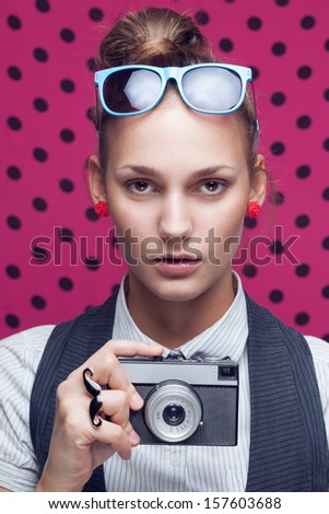 Fashionable teen with old camera in checkered red shirt and bow-tie.