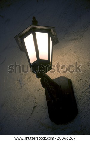 Vertical image of a lit porch light in the evening