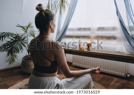 Self-care, self-compassion, mental wellbeing in post-pandemic world. Mental health, wellbeing, meditation to eliminate anxiety. Young woman sitting on floor do yoga exercise and meditation at home.