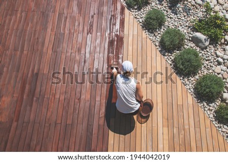 Wood deck renovation treatment, the person applying protective wood stain with a brush, overhead view of ipe hardwood decking restoration process Foto stock © 