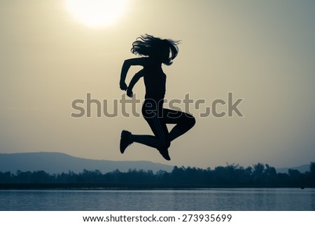 Silhouette of girl jumping in the nature on sunset sky.