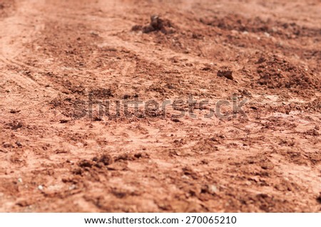 Plowed soil textured surface with grooves under bright sunlight
