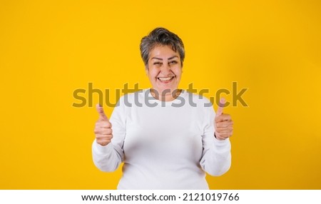 latin matured woman portrait with thumbs up on yellow background in Mexico Latin America Stok fotoğraf © 