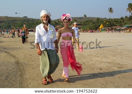 GOA, INDIA - FEB. 24: Couple walking along the beach in the eastern colorful clothes at the annual festival of Freaks on FEB. 24, 2014 in Arambol beach, Goa, India