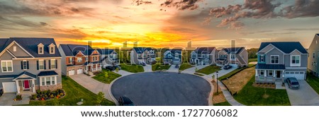 Cul de sac classic dead end street surrounded by luxury two story single family homes in a new residential East Coast USA real estate development neighborhood with dramatic colorful sunset sky