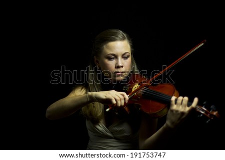 beautiful blue-eyed girl playing the red violin in the dark