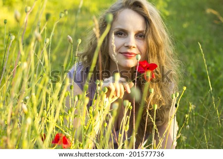 Beautiful happy girl enjoying the sun in the poppy fields. Woman outdoors. Sunrays in the hair. Country style. Flower Fields. Free happy woman