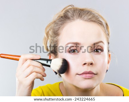 beautiful blonde girl does makeup. Girl apply cosmetic powder. Portrait of a girl.