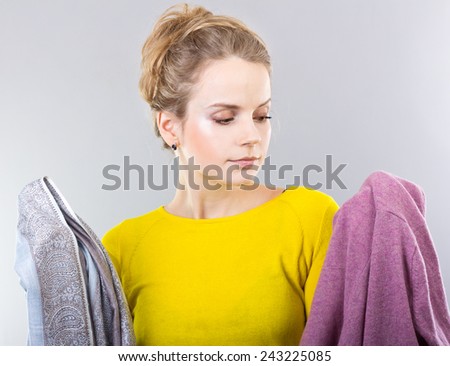 young blonde with clothes in hands.Hostess thinks how to save clothes. Means for care of clothes, washing powder, conditioner for clothes. Shopping