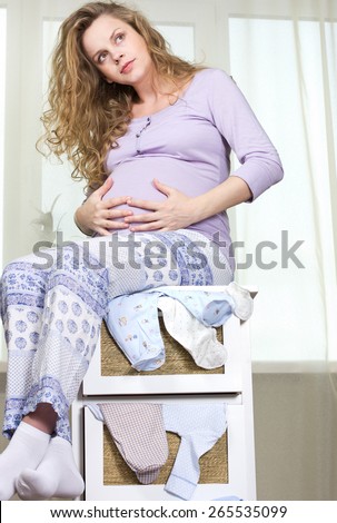 beautiful pregnant blond woman with a big belly at home