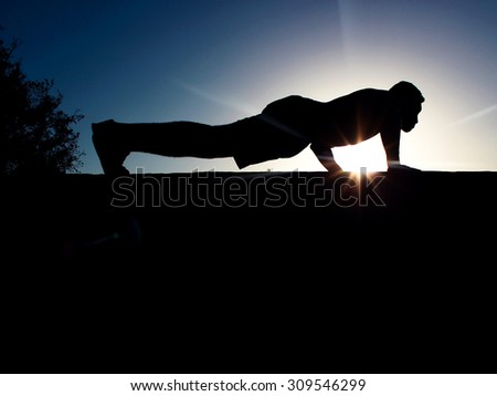 one man exercising fitness workout push ups in silhouette on nature background