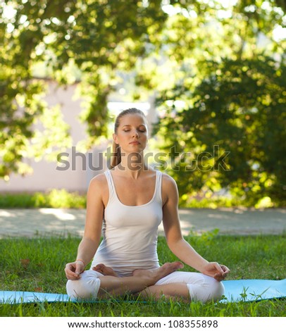 Beautiful woman practices yoga in nature. Lotus Pose, eyes closed