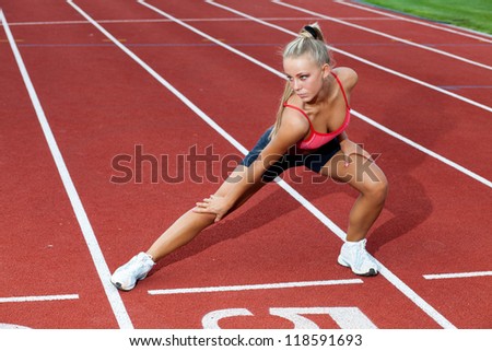 Beautiful young woman in a sports suit doing training exercises before running