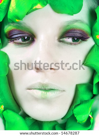 The face of beautiful young girl is surrounded by petals of green rose