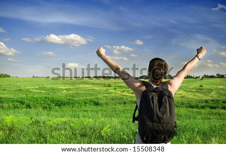 Man winner traveler on the meadow with green grass and blue sky