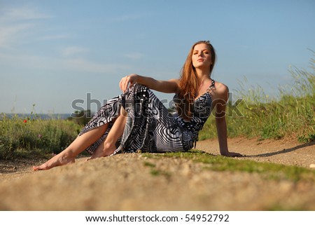 young beautiful woman in dress sitting on the road