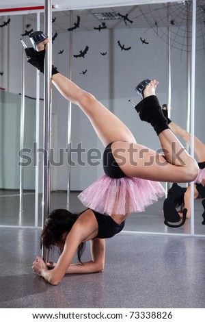 Young athletic woman dancing around the pole