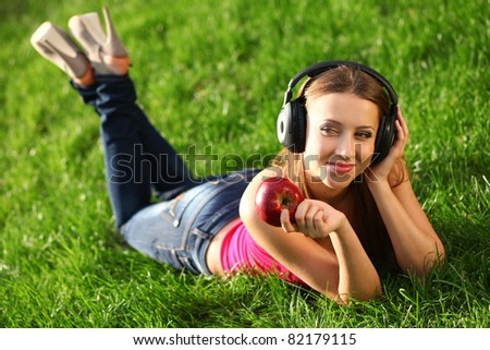 Woman with headphones listening music on the grass