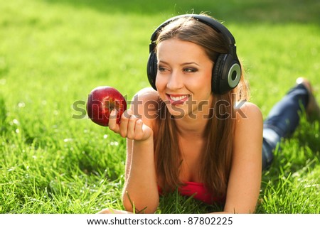 Woman with headphones listening music on the grass