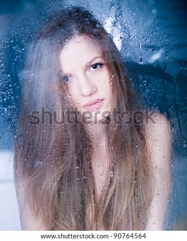 Cute woman behind window with rain drops on window