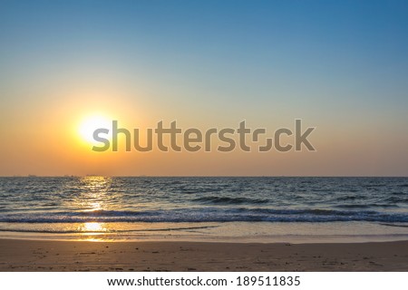 Scenic view from sand beach in Goa to beautiful sunset above the Arabian sea. Sun reflection on sea surface