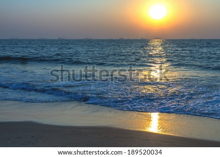 Scenic view from sand beach in Goa to beautiful sunset above the Arabian sea. Sun reflection on sea surface