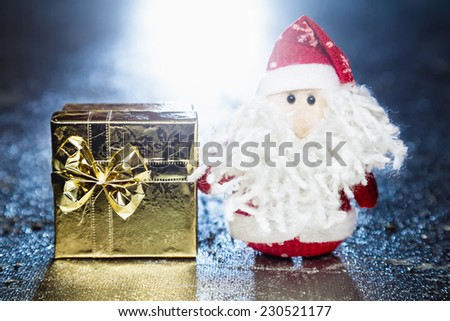 Christmas Santa Claus or Father Frost and gold gift box or present on silver or metal grunge surface with back light from behind