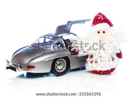 Santa Claus with old vintage automobile on white background with reflection. Main focus of image on Santa Claus and selective on turned the back side and opened right door toy retro car