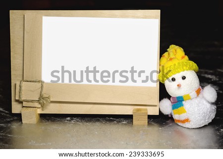 Christmas snowman toy and greeting blank wooden frame on silver or metal grunge surface