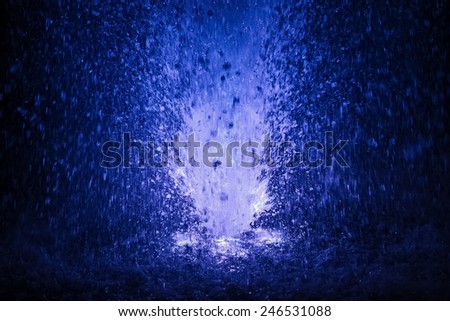 Abstract colorful fountain splashes blue and white color of water drops on a black background. motion blur