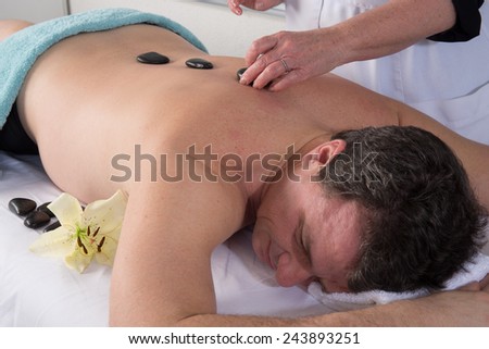 Image of hand placing Lastone on man\'s back in spa