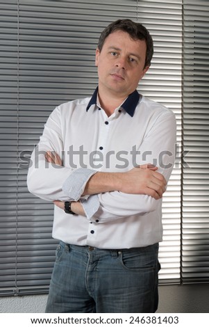 Happy businessman standing behind office desk, angry