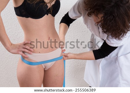 Woman taking the measures of  a young woman who lost weight