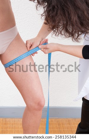 Woman measuring a young woman who has lost weight.