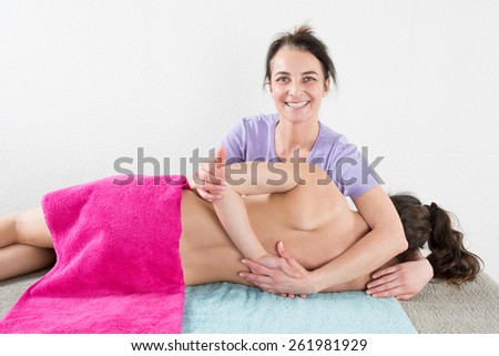 Woman therapist is doing massage on woman back