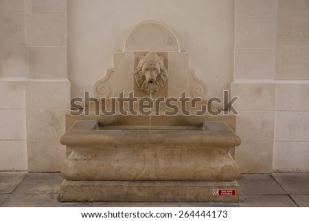 Ancient stone lion head water fountain on an old street