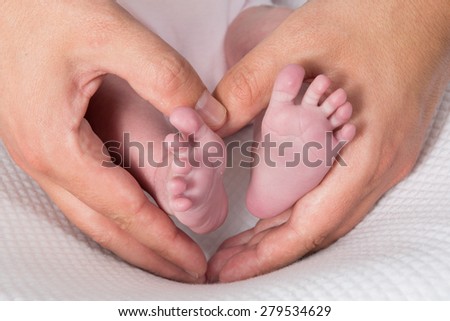 Newborn baby feet on male hands, shape like a lovely heart