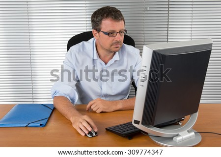 Close-up portrait of a black and grey haired man with computer at desk