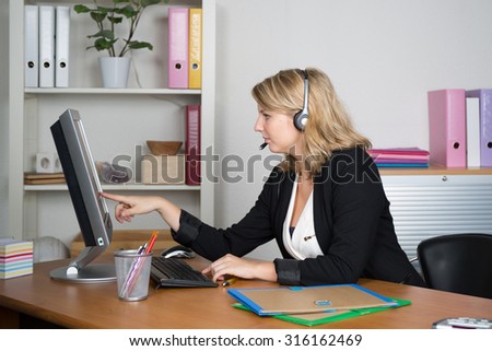 Confident blonde call center agent working on computer in bright office