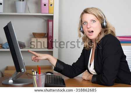 Blonde young woman looking to her computer being surprised