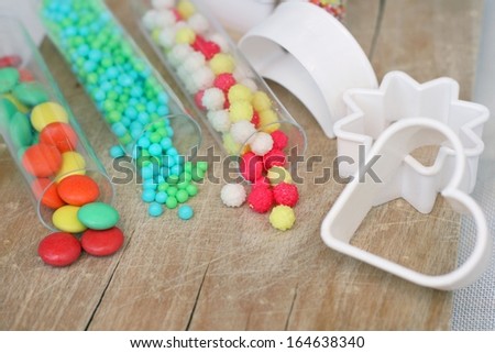 Sweet bright colored candy for children's cookies and cake decoration on wooden table with plastic white cookie cutters