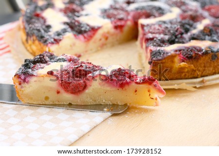 Piece of raspberry, blueberry and blackberry pie with curd and milk cream and powdered sugar