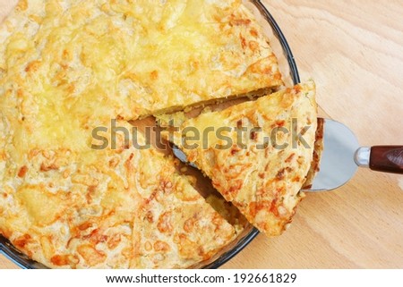 Piece of salty leek pie with cheese and nutmeg in glass dish, homemade, photo from above