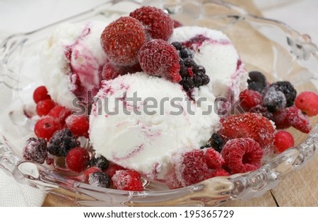Home made yogurt ice cream with frozen berries on glass plate