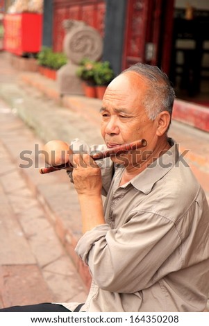 CHENGDU CHINA - May 3:Unidentified handicapped man plays traditional Chinese instrument in Hakka Luodai village - May 3,2012 in Chengdu China.Luodai is an ancient town with its 1000 year history.